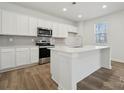 Bright kitchen with stainless steel appliances, island with sink, white cabinets, and hardwood floors at 2576 Blue Sky Meadows Dr, Monroe, NC 28110