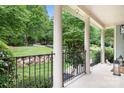 Picturesque front porch featuring classic columns, wrought iron railings, and a serene view of the landscaped yard at 7191 Grist Mill Ct, Denver, NC 28037