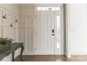 Bright entryway featuring wainscoting wall accents, dark wood floors and a white front door at 8008 Breckenhill Ln, Tega Cay, SC 29708