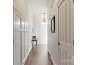 Hallway featuring wainscoting wall accents, dark wood floors and a pendant light at 8008 Breckenhill Ln, Tega Cay, SC 29708