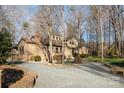 Beautiful home showcasing a long driveway and lush landscaping surrounded by mature trees at 1006 Lost Cv, Weddington, NC 28104