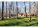 Exterior of a home with lush green lawn and mature trees creating a serene, wooded backdrop at 1006 Lost Cv, Weddington, NC 28104