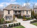 Stately stone home boasts refined design, including manicured landscaping, bay windows, and a welcoming driveway, all under a bright sky at 1238 Ladera Dr, Waxhaw, NC 28173
