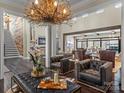 Spacious living room featuring dark hardwood floors, leather seating, a stone fireplace, and a unique chandelier as a focal point at 1238 Ladera Dr, Waxhaw, NC 28173