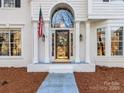 Close up of the front door, featuring an arched window, American flag, and elegant details at 12813 Angel Oak Dr, Huntersville, NC 28078