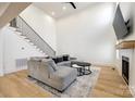 Bright living room with a gray sectional sofa, tall ceilings, and a modern staircase at 2143 Country Club Rd, Lincolnton, NC 28092