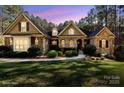 Charming brick home featuring manicured landscaping, symmetrical design, and warm exterior lighting at 4905 River Hills Dr, Denver, NC 28037