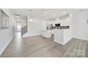 Open-concept living room with gray wood floors, modern lighting, and an adjacent kitchen space at 6814 Piper Thorn Way, Indian Land, SC 29707