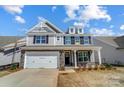 Charming two-story home with stone accents, shingle siding, white garage door, and manicured landscaping at 8720 Acadia Pkwy # 597, Sherrills Ford, NC 28673