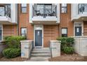 Close up of townhome brick front entrance with concrete steps and a small wrought iron balcony above at 946 E 8Th St, Charlotte, NC 28204