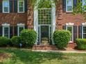 Close up of the brick two-story home's front entrance with a large window and green manicured bushes at 9743 Aegean Ct, Huntersville, NC 28078