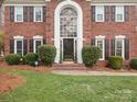 Welcoming front entrance with a brick facade, manicured bushes and an arched window, creating an inviting curb appeal at 9743 Aegean Ct, Huntersville, NC 28078