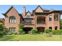 Beautiful backyard view showcasing a brick home with balconies and a well-manicured lawn at 16824 Ashton Oaks Dr, Charlotte, NC 28278