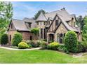 Charming two-story home with a turret, brick and stone facade, lush landscaping and a manicured lawn at 16824 Ashton Oaks Dr, Charlotte, NC 28278