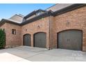 Spacious three-car garage with brick exterior, featuring arched doors and stylish lighting fixtures at 16824 Ashton Oaks Dr, Charlotte, NC 28278