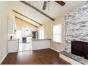 Open-concept living space with hardwood floors, a brick fireplace, and a view of the modern kitchen at 1780 Lumpkin Cir, Rock Hill, SC 29732