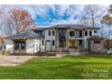 Striking two-story modern home with a combination of stone and white facade, well-manicured lawn, and mature trees at 180 Willow Point Rd, Troutman, NC 28166