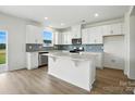 Bright kitchen featuring white cabinetry, stainless steel appliances, blue backsplash, and an island with countertop seating at 330 Knotty Wood Dr # 67, Monroe, NC 28110