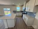 Spacious kitchen features white cabinets, stainless appliances, island, gray backsplash, and natural light at 330 Knotty Wood Dr # 67, Monroe, NC 28110
