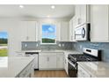 Bright kitchen featuring white cabinetry, stainless steel appliances, blue backsplash, and views from a large window at 330 Knotty Wood Dr # 67, Monroe, NC 28110