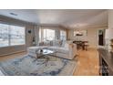 Bright and airy living room featuring a sectional sofa, large windows, and wood floors with a view into the dining area at 5009 Sharon Rd # E, Charlotte, NC 28210