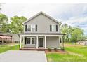 Inviting two-story home boasts a gray exterior, black shutters, a cozy front porch, and a well-manicured front yard at 1412 Meadow Ave, Kannapolis, NC 28083