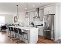 Open kitchen boasts gray cabinets, a stainless steel refrigerator, a center island with seating, and modern pendant lighting at 2014 Bryant Park Dr, Charlotte, NC 28208