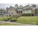 A beautifully landscaped front yard leads to a classic brick home with a welcoming front porch and manicured bushes at 5002 Stonehill Ln, Matthews, NC 28104