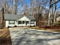 Charming single-story home with white siding, gray roof, and a concrete driveway surrounded by a wooded landscape at 514 Meadowrock Dr, Albemarle, NC 28001