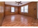 Spacious living room featuring wood paneling, ceiling fan, and ample natural light from two windows at 132 Kennedy Ave, Kannapolis, NC 28083