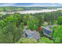 Stunning aerial view of a blue home nestled in lush greenery, near a tranquil lake at 208 Cape August Pl, Belmont, NC 28012