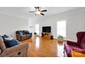 Open living room featuring wood floors, a ceiling fan, and ample natural light from multiple windows at 662 Georgie St, Troutman, NC 28166