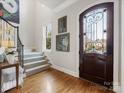 Elegant entryway featuring hardwood floors, a staircase, and a stylish front door at 6711 Conservatory Ln, Charlotte, NC 28210
