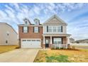 Inviting two-story home with a covered porch, brick facade, and attached two-car garage at 9203 Mackinaw Dr, Gastonia, NC 28056