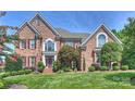 Charming brick facade, symmetrical design, and verdant landscaping create a stately yet inviting home exterior at 9316 Whispering Wind Dr, Charlotte, NC 28277