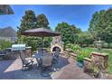Stone patio area with a built-in grill, fireplace, dining table, and umbrella for luxurious outdoor living at 9316 Whispering Wind Dr, Charlotte, NC 28277