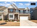 Charming two-story home with a brick and blue siding exterior, complemented by a well-manicured lawn and an attached two-car garage at 1051 Lookout Shoals Dr, Fort Mill, SC 29715