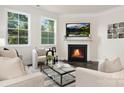 Bright living room with large windows, a cozy fireplace, and comfortable seating arrangement, creating an inviting atmosphere at 111 Noah Ln, Troutman, NC 28166