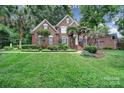 Beautiful two-story brick home with lush landscaping, a well-manicured lawn, and mature trees at 907 Thorn Ridge Ln, Lake Wylie, SC 29710