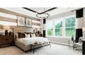 Bright main bedroom featuring large windows, a decorative chandelier, and stylish striped accent wall at 1043 Rabbit Hill Ln, Monroe, NC 28110