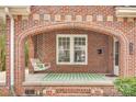 Close-up view of a brick-arched porch featuring a swing and green striped rug at 119 Hemphill Ave, Chester, SC 29706