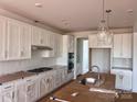Bright kitchen features white cabinets, subway tile backsplash, stainless appliances, and island with sink at 13248 Chopin Ridge Rd, Huntersville, NC 28078
