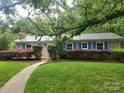 Charming single-story brick home with a metal roof, lush landscaping, and a walkway leading to the front door at 1552 10Th Street Nw Pl, Hickory, NC 28601