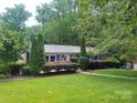 Charming one-story home featuring a metal roof, blue shutters, and beautiful landscaping at 1552 10Th Street Nw Pl, Hickory, NC 28601