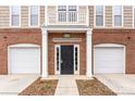 Townhome entrance with a black door, white columns, and two-car garages on either side at 6464 Park Pond Dr # 7, Charlotte, NC 28262