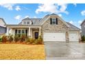 Charming home with a stone facade, three-car garage, and manicured landscaping at 6858 Hunts Mesa Dr, Fort Mill, SC 29707