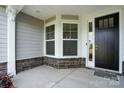 View of the front porch with stone accents, gray siding, a front storm door and manicured landscaping at 8716 Acadia Pkwy # 596, Sherrills Ford, NC 28673