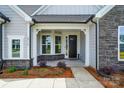 Covered front porch with stone accents, gray siding, a front storm door and manicured landscaping at 8716 Acadia Pkwy # 596, Sherrills Ford, NC 28673