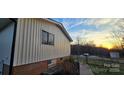 Exterior side view of the home featuring siding, brick foundation, and a glimpse of the sunset at 1024 Old Mountain View Rd, Mount Holly, NC 28120