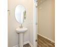 Powder room with a pedestal sink, a large oval mirror, and hardwood floors at 1758 Braemar Village Dr, Monroe, NC 28110